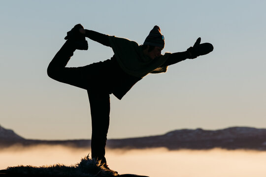 Woman practicing yoga outdoors in winter mountain light