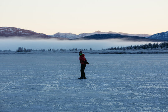 Ice skating on frozen lake in Nordic winter landscape
