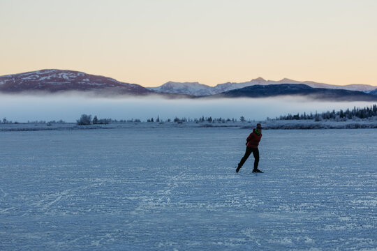 Ice skating on frozen lake in Nordic winter landscape