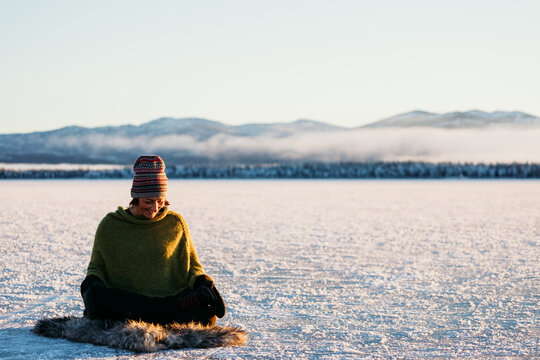 Woman meditating on lake in winter light