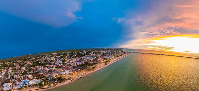 Aerial view of the coastal town of Progreso with its long pier and sandy beach under a dramatic sunset sky Yucatan, Mexico.