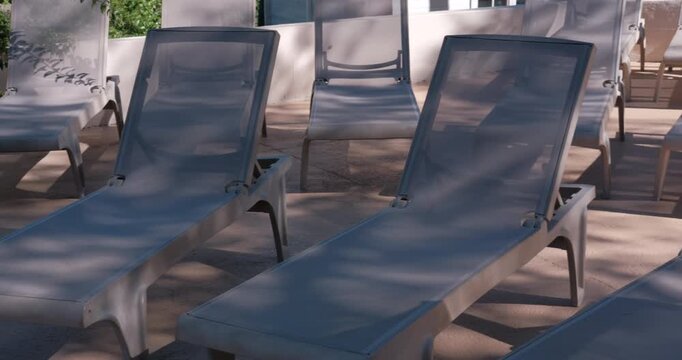 PORTOCOLOM, MALLORCA, SPAIN - OCTOBER, 2025: Empty sun loungers with strong midday sun and shadow contrast, bright day for relaxation