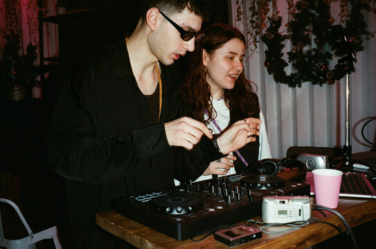 DJ Duo Operating Mixer and Drum Pad at Intimate Party Venue