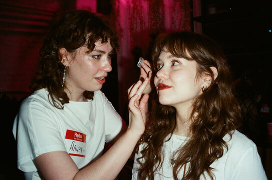 Two Friends Applying Glitter Makeup at Party, Pink Neon Light