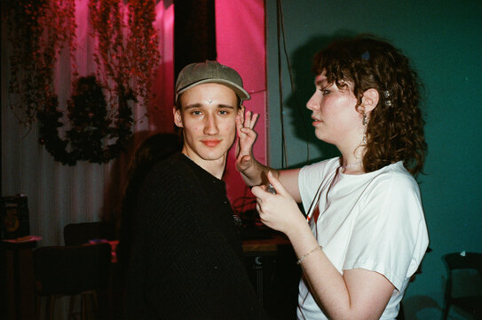 Two Young Friends at Party Under Pink and Teal Neon Lights