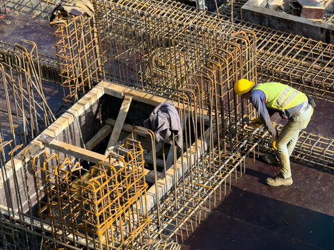 Construction Worker with Helmet Binding Steel Rebars at Site
