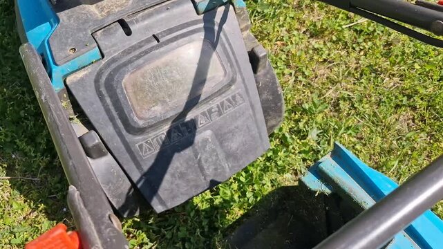 Person removing the full grass box from an electric lawnmower