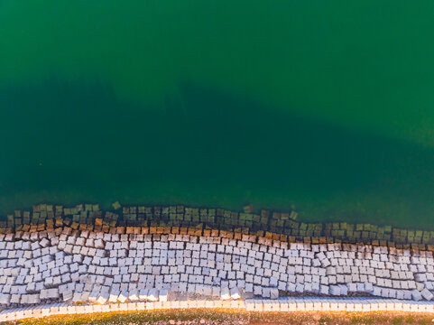Aerial view of geometric concrete breakwater blocks along the emerald shoreline of the Peninsula de Yucatan Yucatan, Mexico.