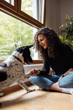 Smiling Woman And Dog Bonding By Sunny Window