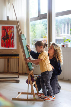 Child Painting at Easel With Caregiver in Studio