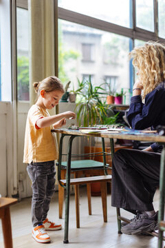 Young Child Playing Board Game With Adult At Table