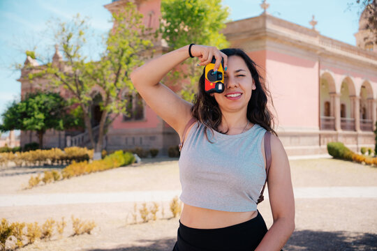 Smiling woman with a compact camera in front of a historic palace.