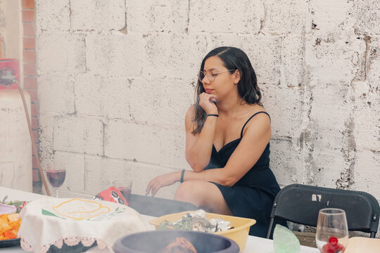 Thoughtful woman sitting at the table during an outdoor meal.
