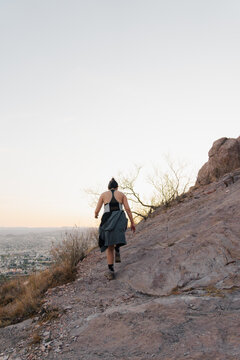 Woman climbing a rocky mountain at sunset.