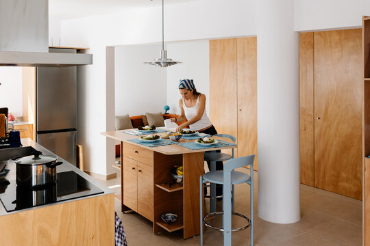 Woman setting up a dining table for a salad meal with friends