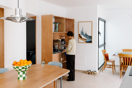 Woman making coffee with her coffee maker in the living room