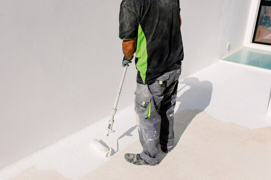 Unknow painter using a paint roller to cover the floor of a terrace