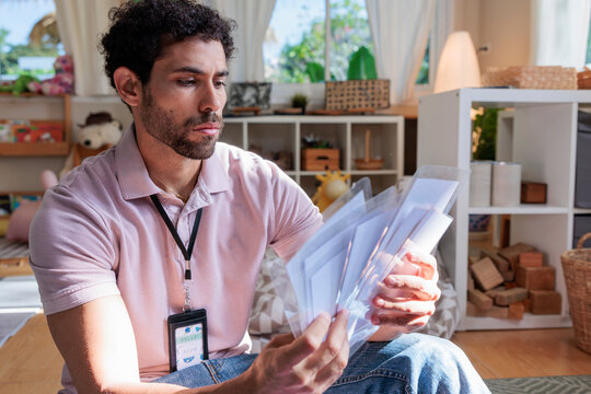 Man with ID badge reviews papers in a playroom.