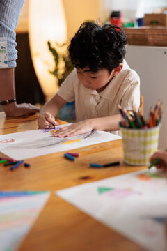 Child drawing with crayons at a table.
