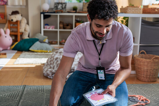 Man with flashcards in a child-friendly room.
