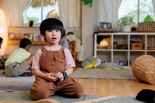 Young boy in overalls plays in a bright playroom.