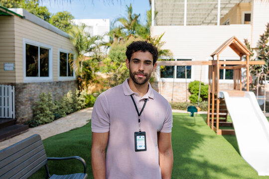 Man with ID badge stands in playground setting.