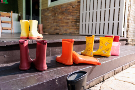 Colorful rain boots lined up on a porch.