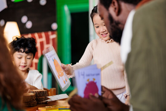 Children learn with teacher using monster-themed flashcards.