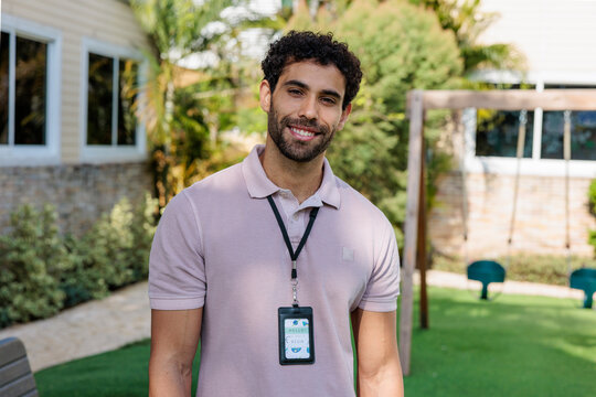 Smiling man with ID badge in a backyard setting.