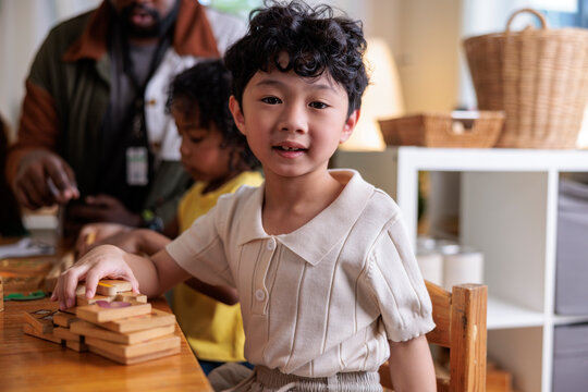 Child smiles while playing with wooden blocks at school.
