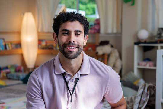 Smiling man in pink polo shirt in a room.