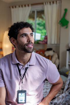 Man with name tag looks thoughtfully toward window.