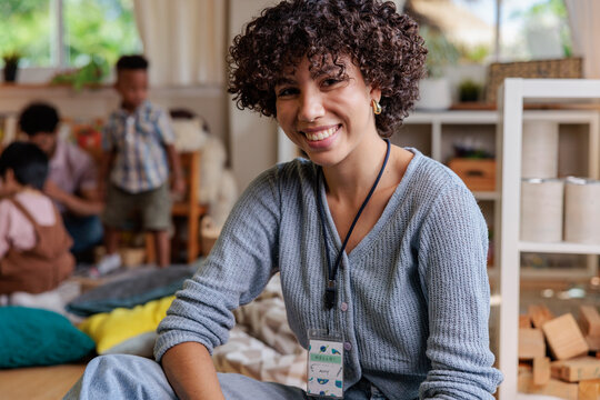 Smiling teacher with children in a classroom setting.