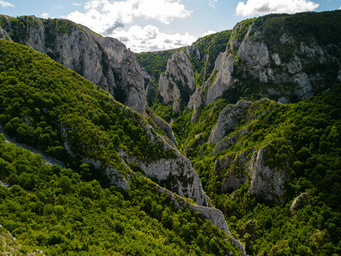 Aerial view of the dramatic limestone cliffs and lush green canyon of Turda Gorge, scenic mountain landscape of Cheile Turzii nature reserve in Transylvania, Romania