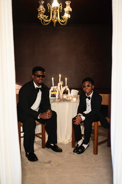 Two People Dressed in Formal Wear Sit at a Table With Candles