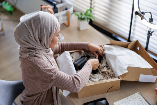 Woman in hijab unboxing products for online business.