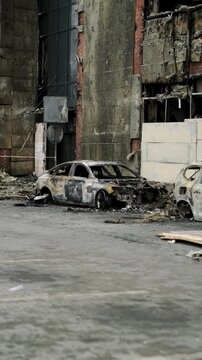 Burned out car wreck abandoned on city street. Destroyed vehicle after fire accident. Vehicle hulk as result of war conflict or arson. Urban catastrophe and property damage concept.