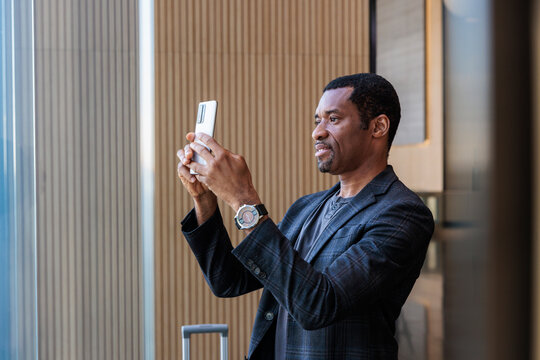 Man takes photo with phone in modern building.