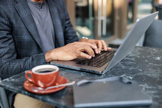 Man works on laptop with coffee nearby.