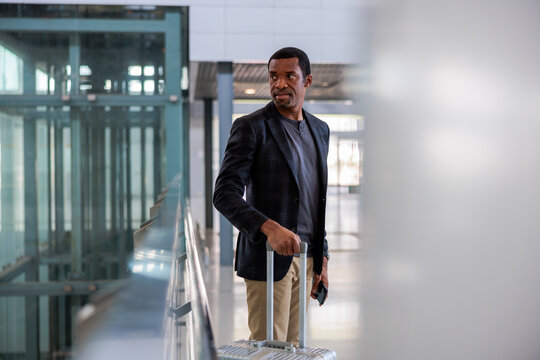 Man with suitcase looks back in modern building.