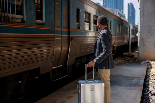 Man with suitcase waits for train at station