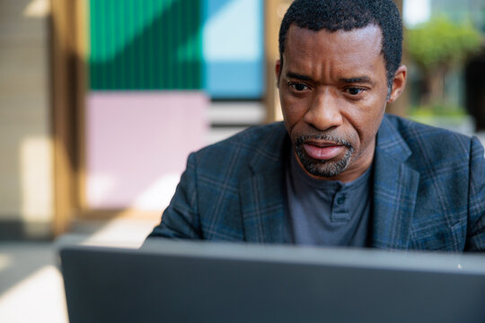 Man intently focused on laptop screen, looking concerned.