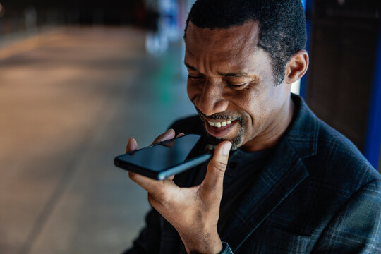 Man smiling while using voice assistant on his phone.