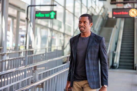 Man in blazer at modern transit station.
