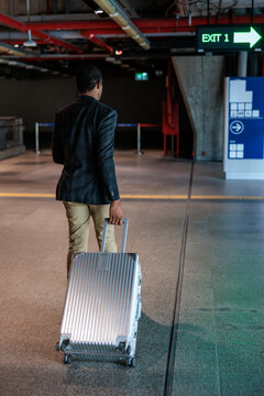 Man with suitcase follows exit sign in modern station.