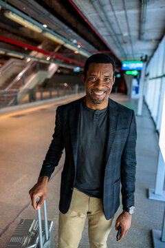 Smiling traveler with luggage at airport or train station.