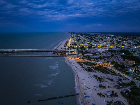 Aerial view of the coastal city at twilight with a long pier stretching into the sea and glowing street lights along the beach Yucatan, Mexico.
