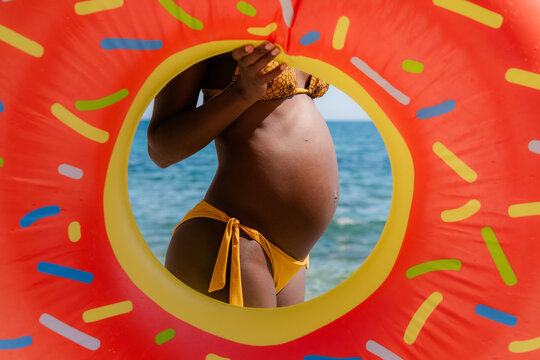 Woman in Bikini Standing by the Sea With a Donut Float