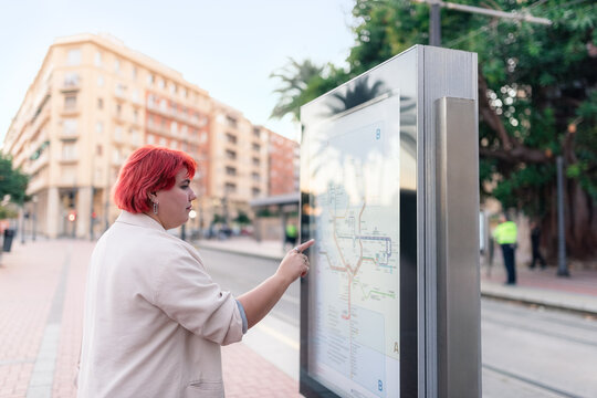 Woman Looks at Transit Map in the City on a Sunny Day
