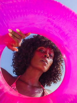 Woman looking at camera through swim ring 